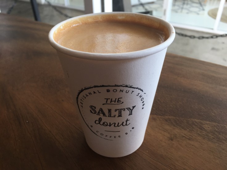 A Cup Filled with a Cinnamon Toast Crunch Latte at The Salty Donut in Miami's Wynwood Art District Sits on a Table