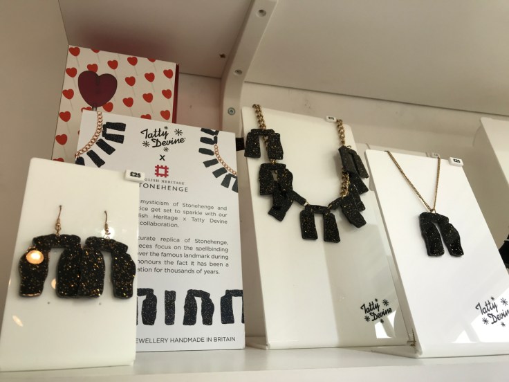 A photo of pieces from the, "Stonehenge," jewelry collection which was a collaboration between English Heritage and Tatty Devine. Tatty Devine is a local shop located in London, England. The pretty plastic jewelry features necklaces and earrings done in black acrylic and flecks of gold designed to look like Stonehenge.