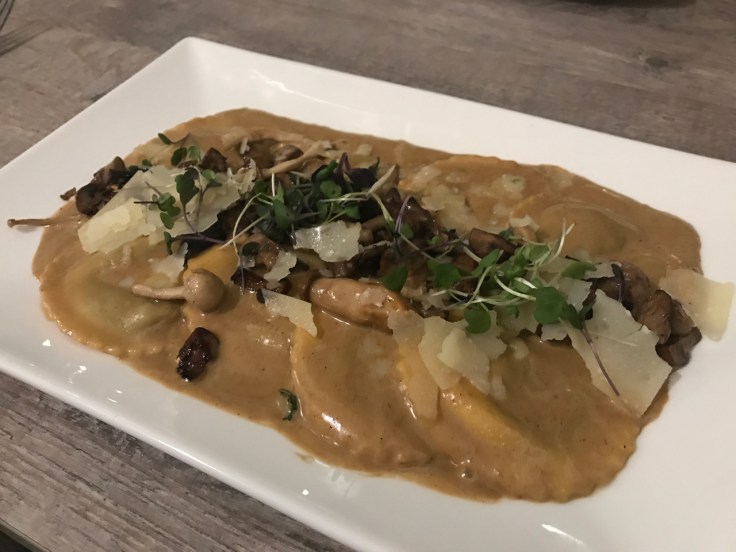 A photo of wild mushroom ravioli on the table at Morsey's Farmhouse Kitchen in Los Altos. The dish features a porcini buffalo cream sauce, shaved parmesan, micro greens and truffle.