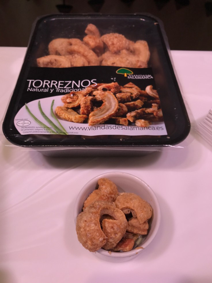 A photo of samples of torreznos on the counter at Viandas De Salamanca in London, England. Torreznos are fried bits of pork belly or pork rind commonly known as pork crackling in the United States.