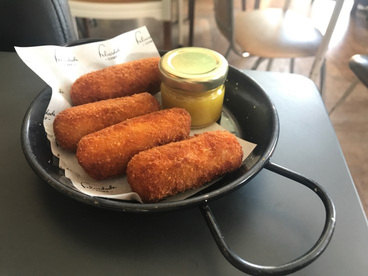 Four Iberian pork croquettes are served with mustard table side at Pharmacia restaurant in Lisbon, Portugal. (Croquete de presunto de porco preto com mostarda)