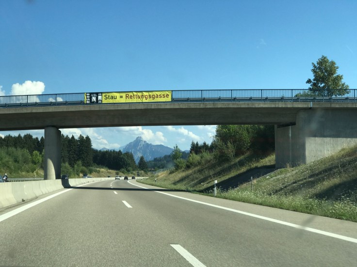A photo of the autobahn during the drive to Neuschwanstein Castle in Germany. You can see the German Alps peeking out above the road.
