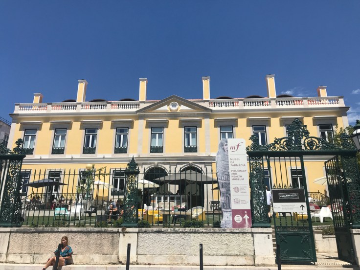 A street view photo from the sidewalk of the exterior of the Associação Nacional de Farmácias (National Association of Pharmacies) building which houses Pharmacia restaurant in Lisbon, Portugal.