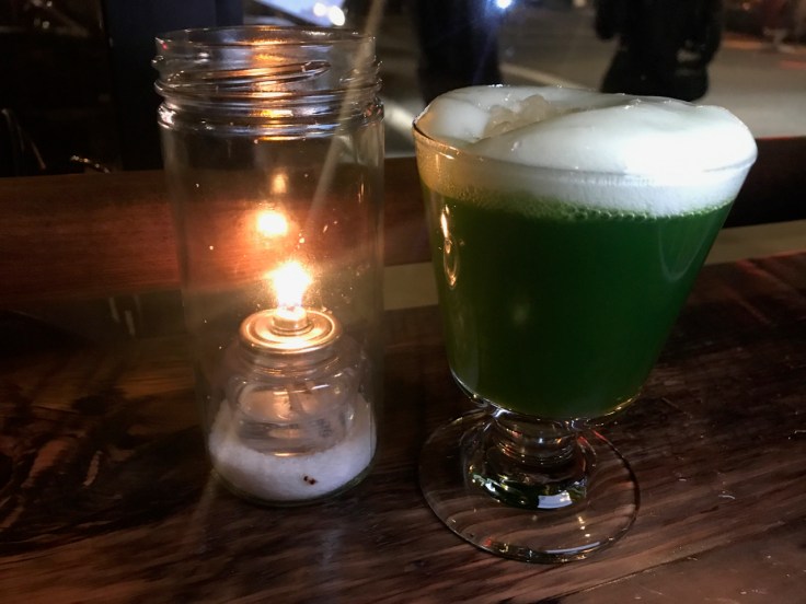 A photo of the dark green aloe vera cocktail at The Snug SF in San Francisco, California. The drink is made with tequila, aloe vera, wheatgrass and lime.