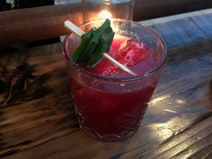 A photo of the blood red hued prickly pear cocktail at The Snug SF in San Francisco, California. The drink is made with mezcal, amaro, nopales, prickly pear, habanero and lime.