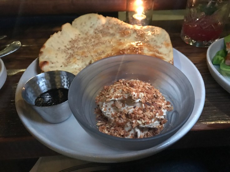 A photo of the sesame naan and shiitake mushroom hummus at The Snug SF in San Francisco, California. The dish also features burnt leeks (on the side) and roasted garlic.