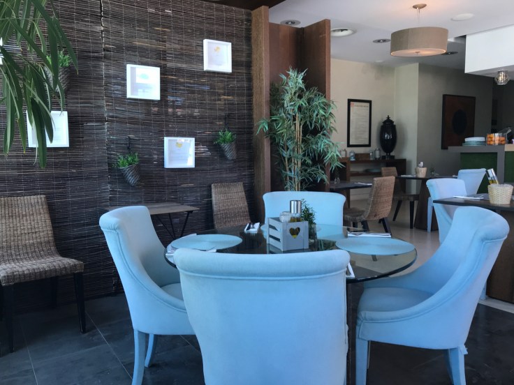 A photo of the inside of the Organic Caffe with its woven chairs and glass tables in Estoril, Portugal.