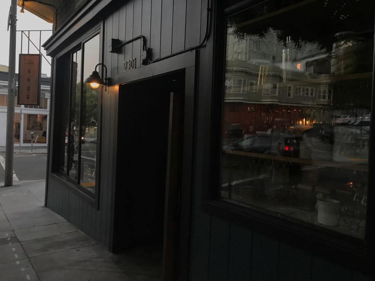 A street view photo of the outside of The Snug SF from the sidewalk in San Francisco, California.