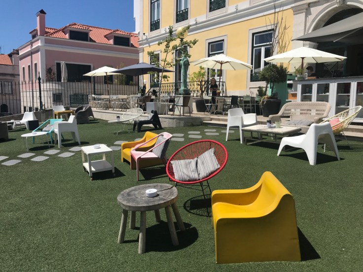 The cheery outdoor patio at Pharmacia restaurant in Lisbon, Portugal is filled with brightly colored chairs and tables.