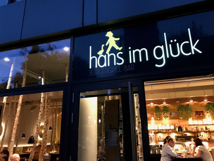 A photo of the exterior outside of Hans im Glück restaurant and burger grill in Stuttgart, Germany take from the sidewalk. Photo Courtesy of FoodWaterShoes