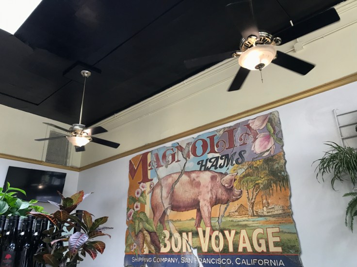 A giant Magnolia Hams sign inside Brenda's Meat & Three restaurant in San Francisco, California. The sign inside this hip breakfast and brunch spot says, "Bon Voyage Shipping Company, San Francisco, California."