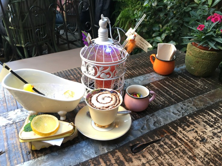 A table at Madrid, Spain's El Jardín de SB (Salvador Bachiller) is decorated with an al agua patos (duck water) cocktail, a mi lindo pajarito (my cute little bird) drink and a cappuccino. The al agua patos is served in a mini bathtub glass with a yellow rubber ducky floating in it. It's made with strawberry vodka, lemon juice and soda (vodka de fresa, jugo de limón y soda). Mi lindo pajarito is made with almond liquor, blackcurrant liquor, dark rum, pineapple juice and lemon juice (licor de almendras, licor de cassis, ron oscuro, jugo de piña y jugo de limón). My cute little bird arrives in its own bird cage with a glowing LED ice cub and with a feathered friend. Photo Courtesy of FoodWaterShoes