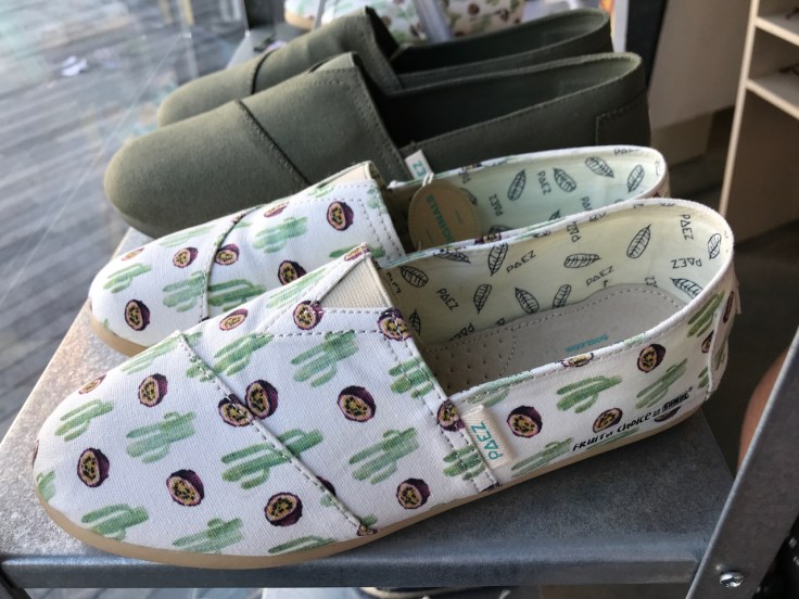 A pair of espadrilles decked out with passion fruit print sit beside green shoes in a window display at the Paez store in Porto, Portugal. Photo Courtesy of FoodWaterShoes