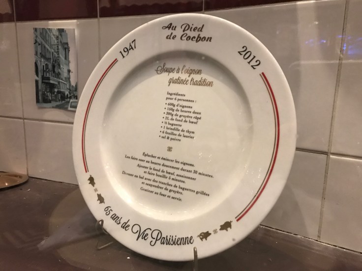 A plate with a traditional French onion soup recipe (soupe à l'oignon gratinée tradition) is on display on a shelf in Au Pied de Cochon restaurant in Paris, France.