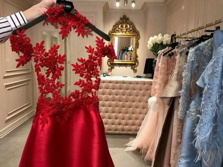 A gorgeous red gown with embroidered flowers that went to the 2018 Cannes film festival. João Rôlo Couture's Daniel Pinheiro is holding the dress by its hanger in the local Lisbon, Portugal boutique. Photo Courtesy of FoodWaterShoes