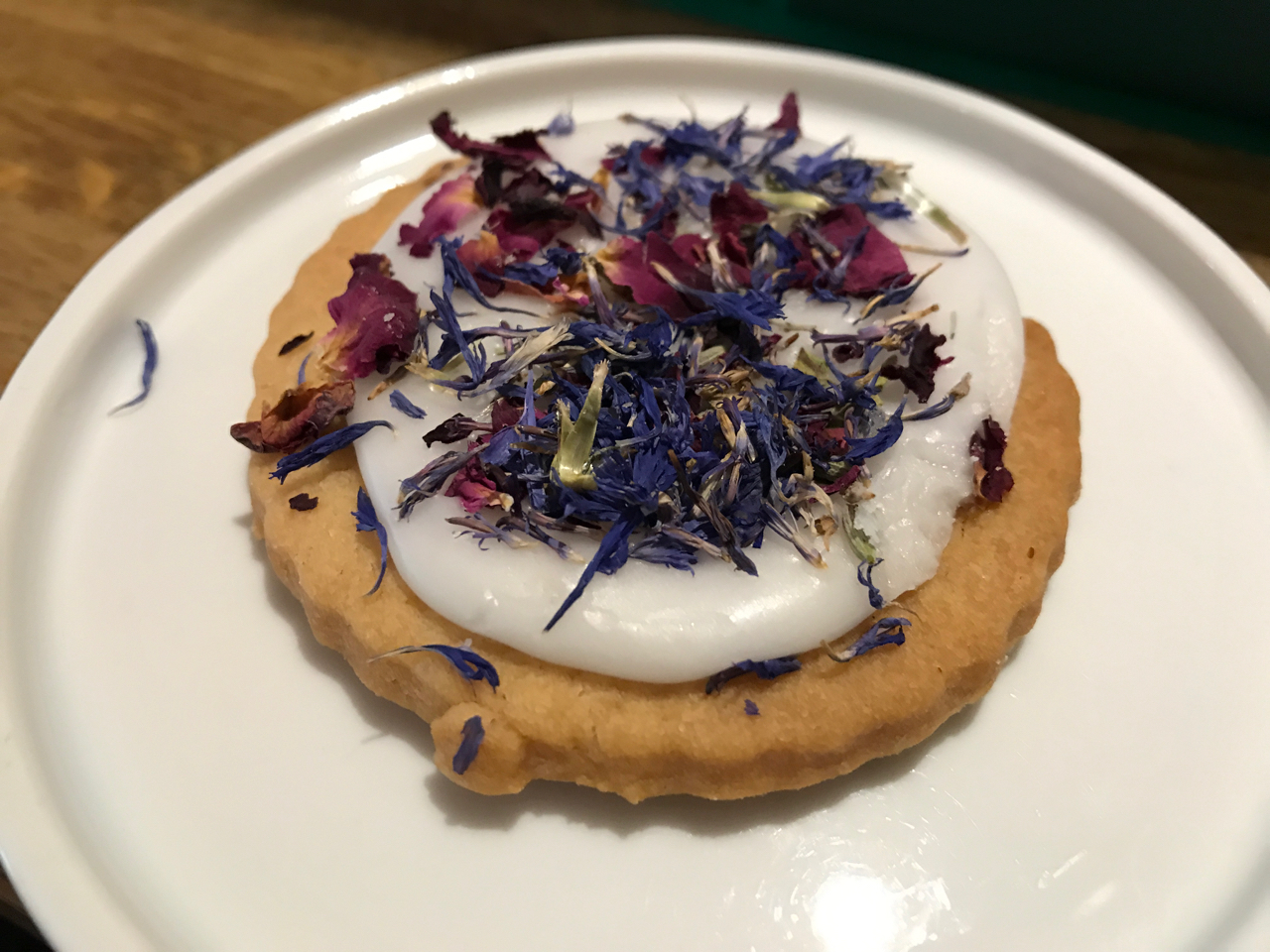 Sablés Aux Fleurs - A stunning shortbread cookie with white icing and purple and pink dried flowers at Peonies Café and Flower Shop in Paris, France.