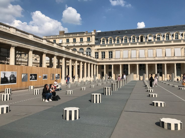 Black and white striped painted columns decorate the inner courtyard of the 17th Century Le Palais Royal (Royal Palace). The art installation is called the Colonnes de Buren (also known as Les Deux Plateaux) in Paris, France. Photo Courtesy of FoodWaterShoes
