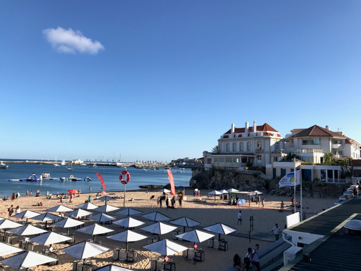 Umbrellas and chairs are set up near the ocean alongside one of the beautiful beaches in Cascais, Portugal. Photo Courtesy of FoodWaterShoes