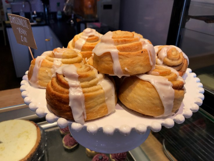 A cake stand holds a bunch of freshly made vegan cinnamon rolls (zimtschnecke) at Katjes Café Grün-Ohr coffee shop in Berlin, Germany. Photo Courtesy of FoodWaterShoes