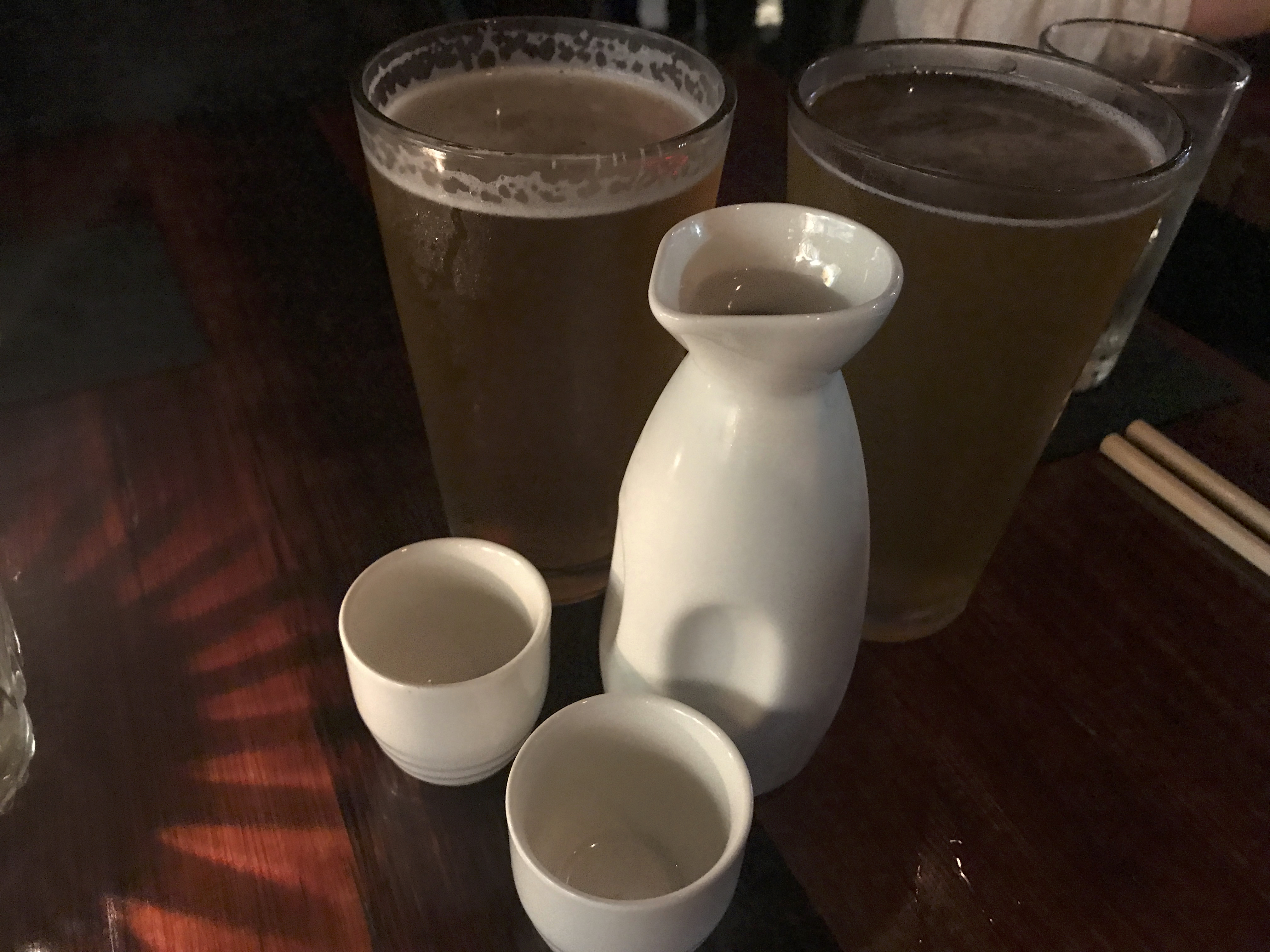 A photo of two pints of Hitachino white ale, a Belgium style white beer from Japan, sitting beside a carafe of house sake at Shōjō, a local Asian restaurant in Boston, Massachusetts' downtown Chinatown. Photo Courtesy of FoodWaterShoes