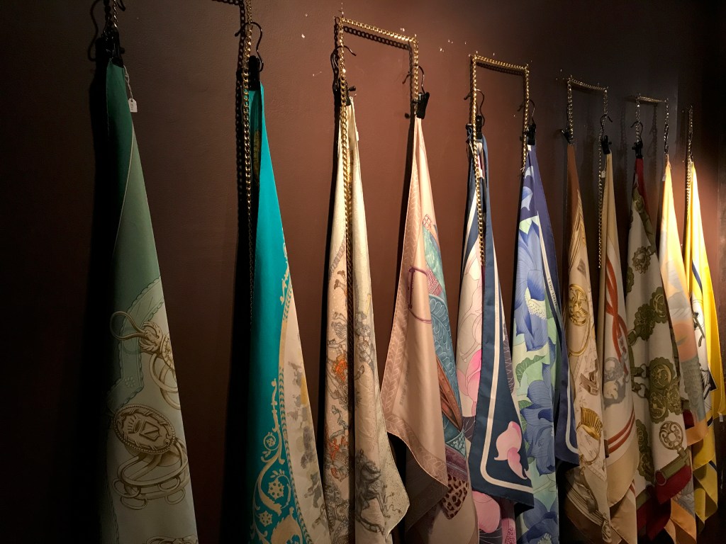 A photo of a glorious collection of vintage silk Hermès scarves at secondhand boutique Isabelle Bajart in Brussels (Bruxelles), Belgium. Photo Courtesy of FoodWaterShoes