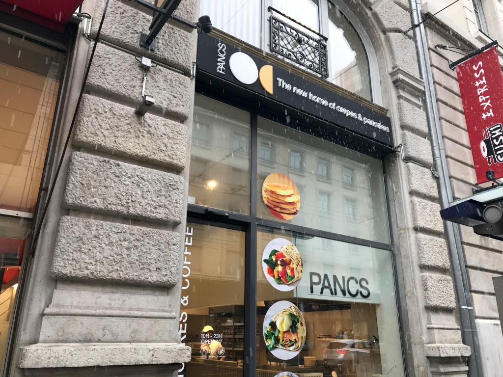 An exterior street view photo of the outside front of Pancs a fast food restaurant in Lausanne, Switzerland. Photo Courtesy of FoodWaterShoes.