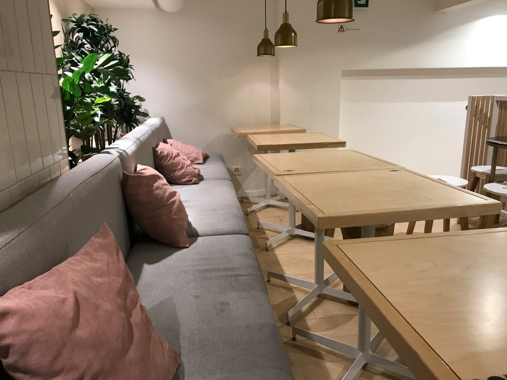 A photo of the grey benches with pink pillows at Pancs, a fast food restaurant that serves chicken pancake burgers in Lausanne, Switzerland. Photo Courtesy of Food WaterShoes