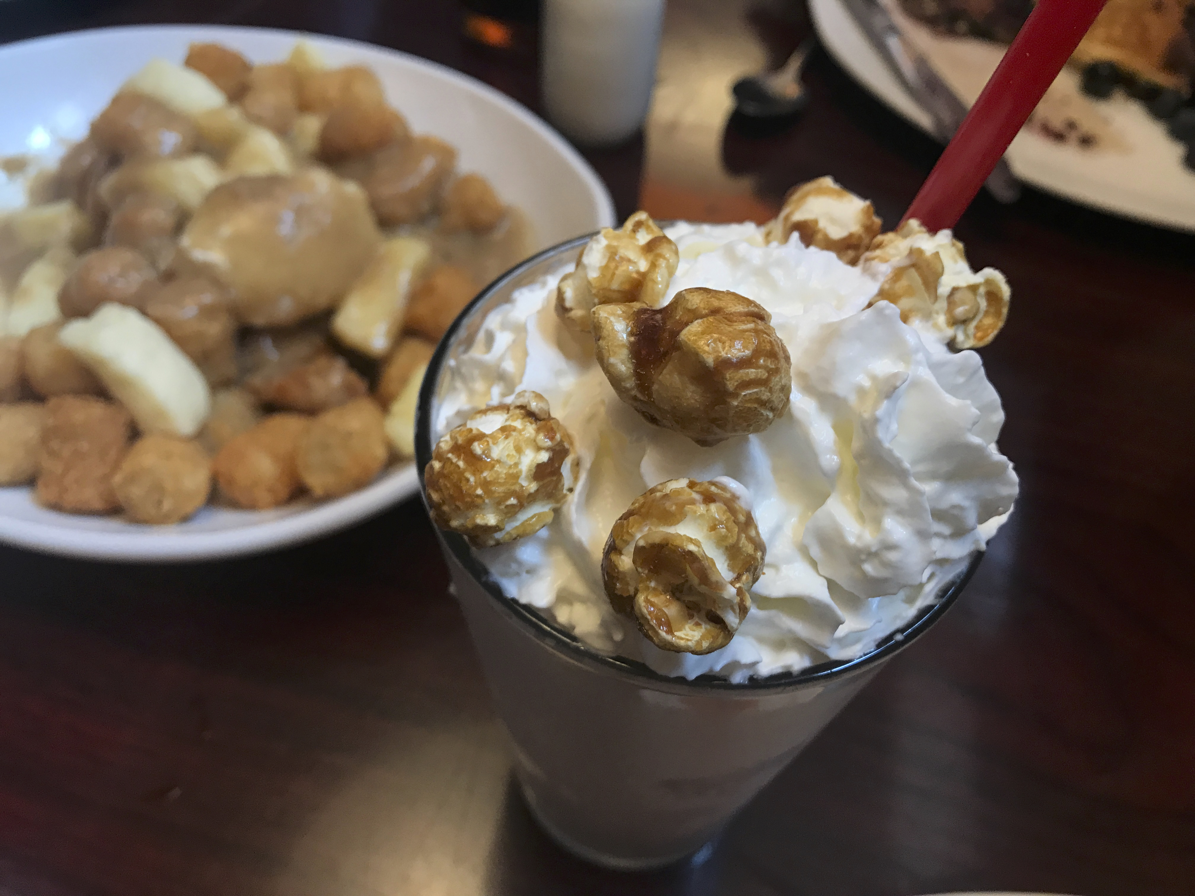 A photo of the salted caramel milkshake at Modern Malt in Downtown Syracuse, New York. The brown hued milkshake features whipped cream and is topped with salted popcorn. Photo Courtesy of FoodWaterShoes