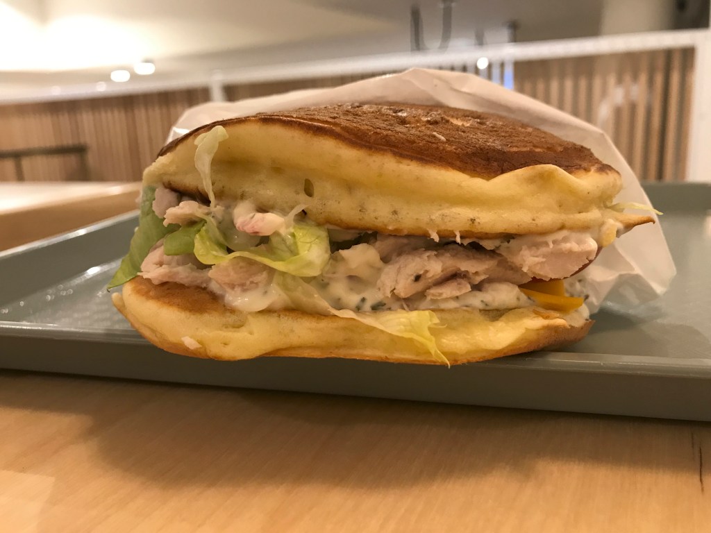 A photo of a chicken pancake burger at Pancs, a fast food restaurant in Lausanne, Switzerland. Is it technically breakfast, lunch or dinner? Weird and strange, but good! Photo Courtesy of FoodWaterShoes