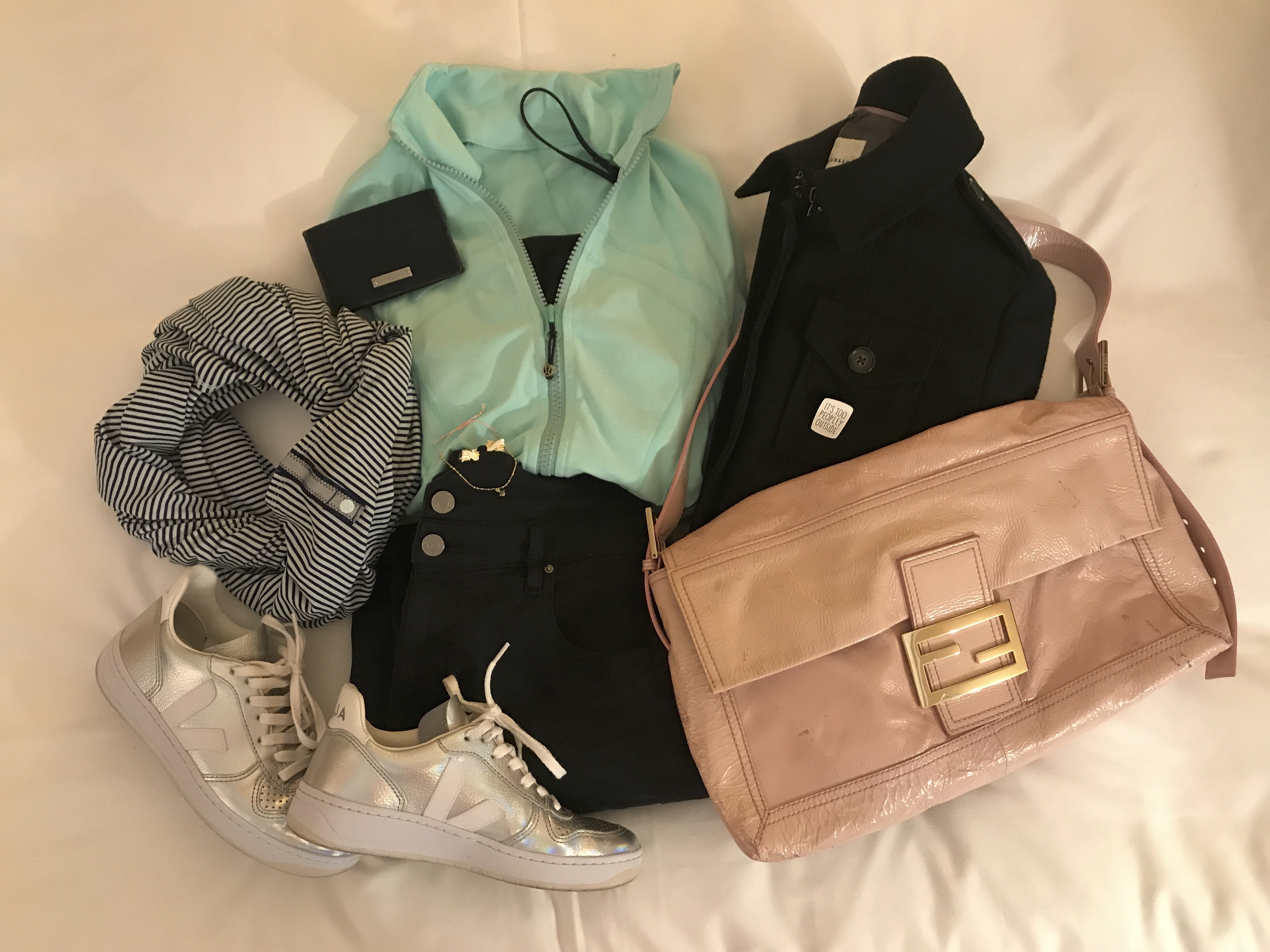 A photo of a Lululemon vinyasa reversible Rulu striped scarf (in hyper stripe sea mist and hero blue), Veja V-10 unicorn sneakers, a large pink Fendi baguette bag, black Isabel Marant high waist denim jeans, a plain black tank top, a black Gucci wallet and a mint forme jacket from Lululemon.