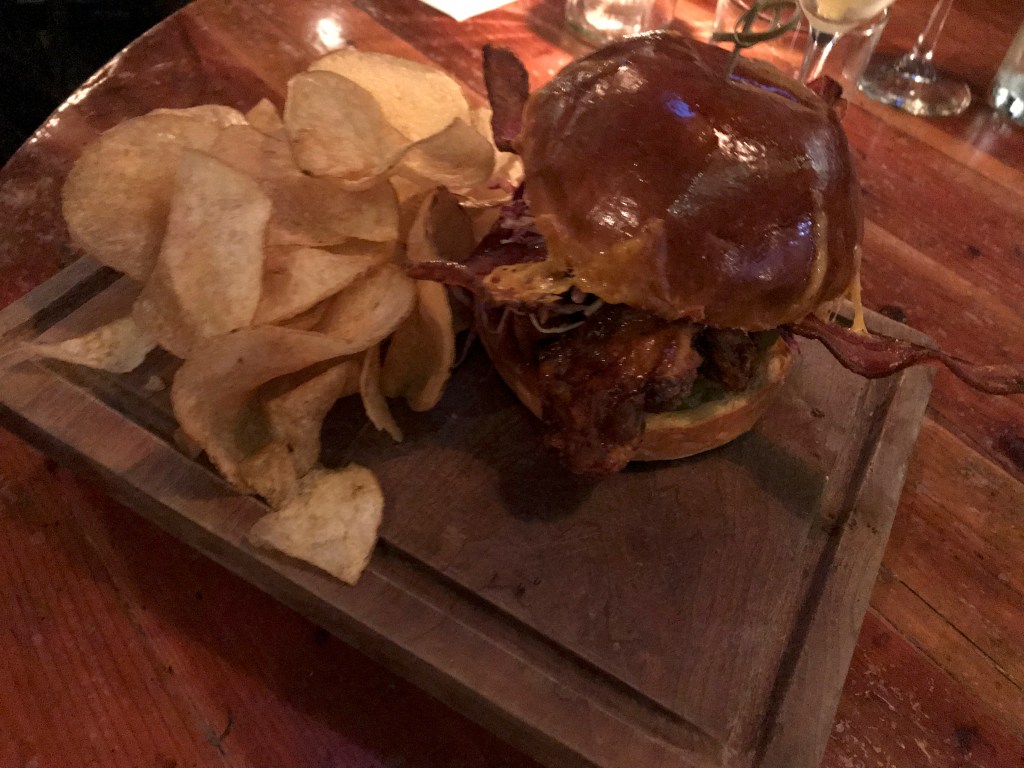 A photo of the fried chicken sandwich at local hot spot Mindy's Hot Chocolate Chicago in Chicago, Illinois. The dish is made with a buttermilk fried chicken thigh, a brioche bun, cheddar, hot sauce maple syrup and served with potato chips as well as house made pickles. The Windy City based dessert restaurant serves brunch, cocktails, drinks, lunch and dinner. Photo Courtesy of FoodWaterShoes