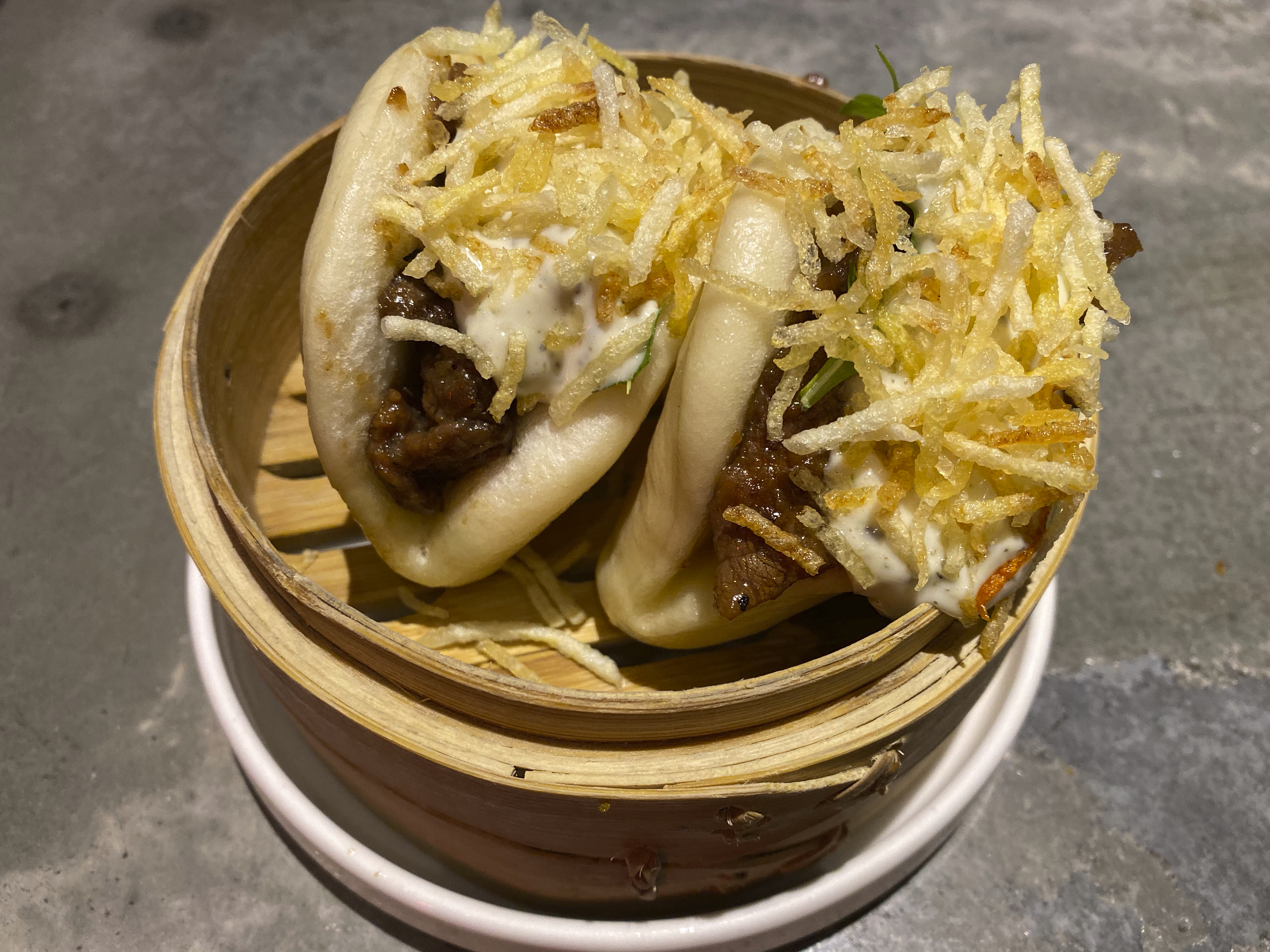 A photo of Mongolian beef baos made with a creamy herb sauce on a table at Baozi باوزي restaurant in Riyadh, Saudi Arabia. Photo Courtesy of FoodWaterShoes