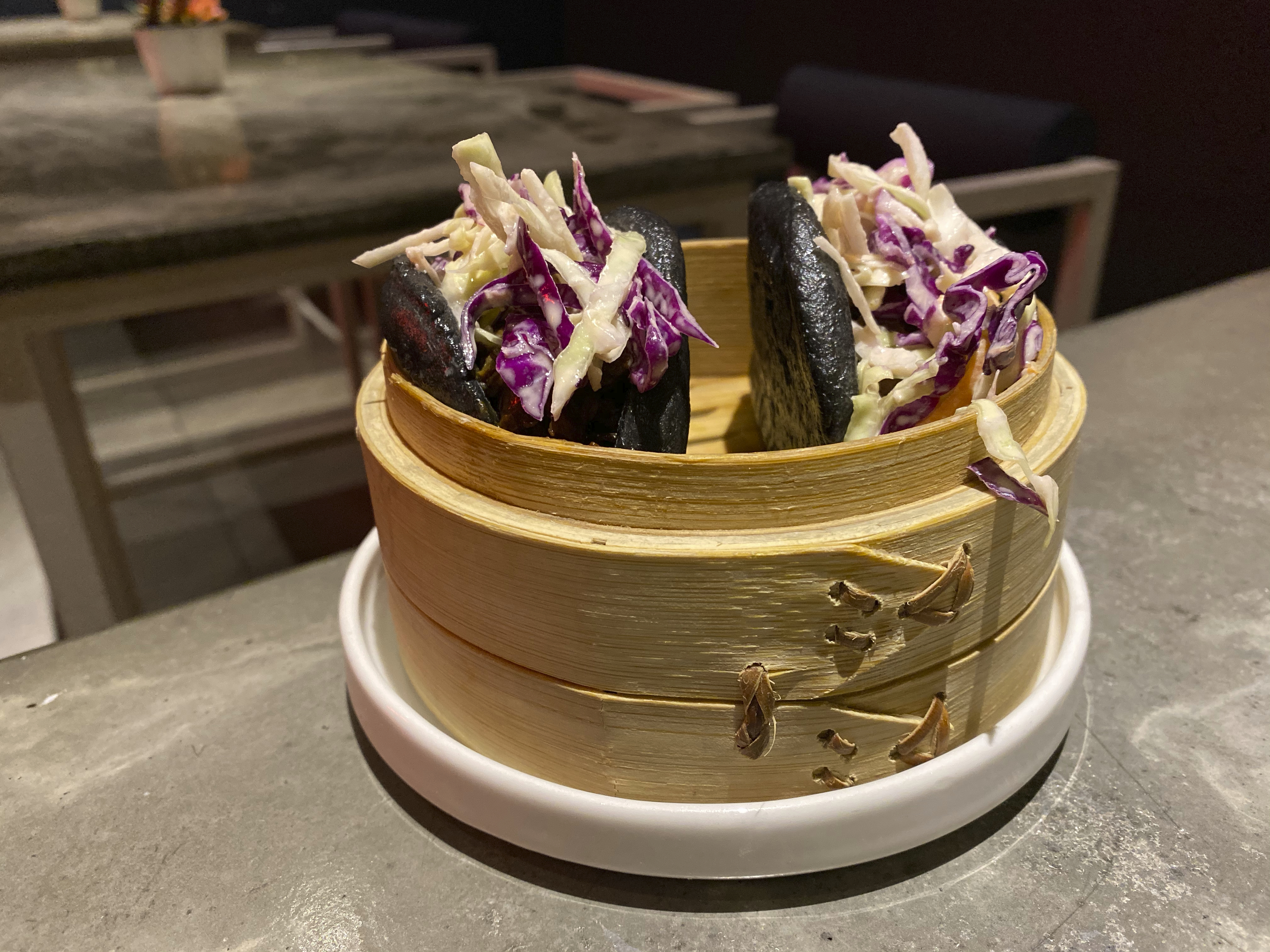 A photo of slow cooked brisket charcoal baos with smoky BBQ barbecue sauce on a table at Baozi باوزي restaurant in Riyadh, Saudi Arabia. Photo Courtesy of FoodWaterShoes