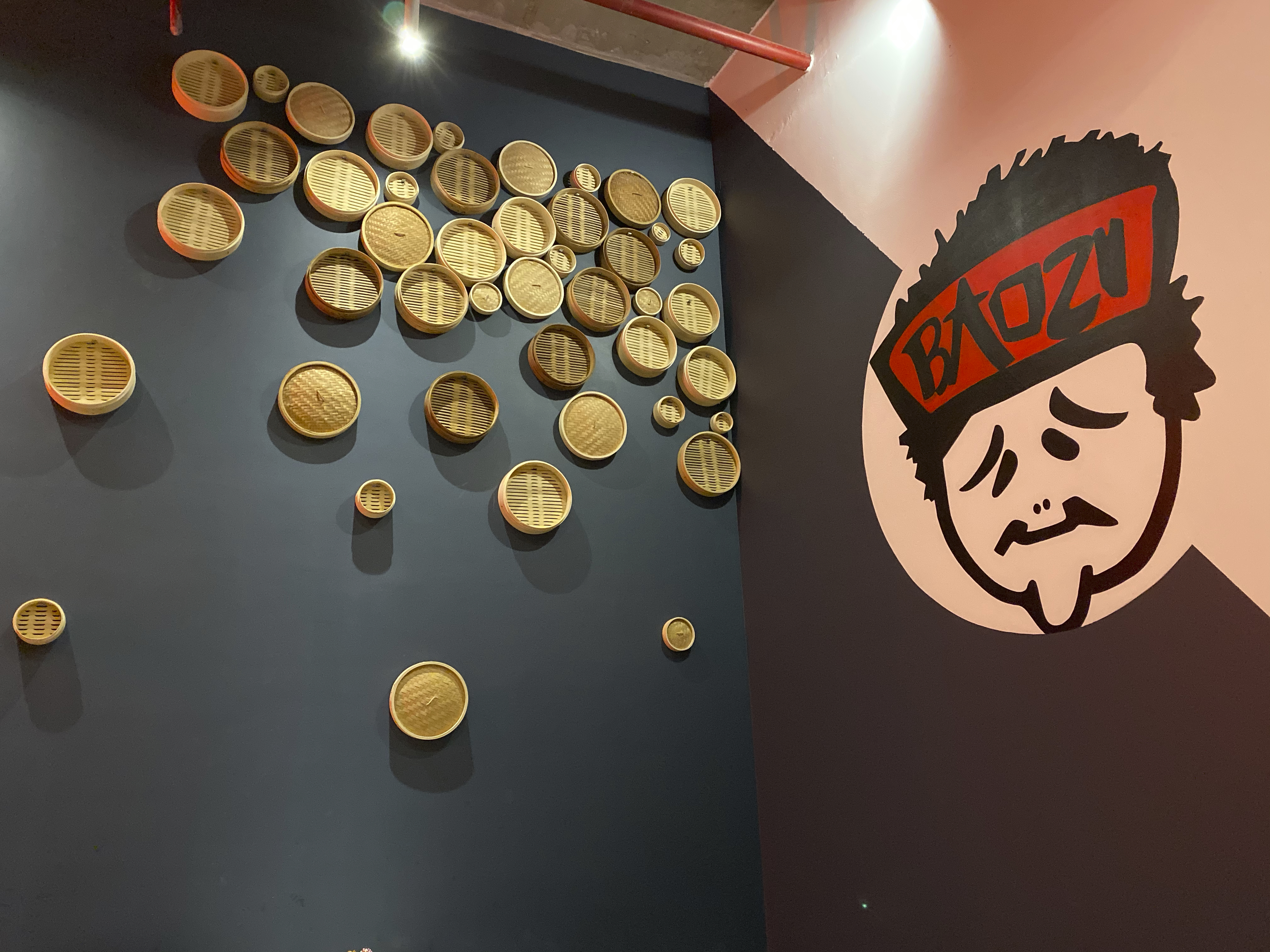 A photo of the inside interior of Baozi باوزي restaurant in Riyadh, Saudi Arabia. Bamboo steam baskets are stuck to the wall and fun cartoon characters decorate the space. Photo Courtesy of FoodWaterShoes