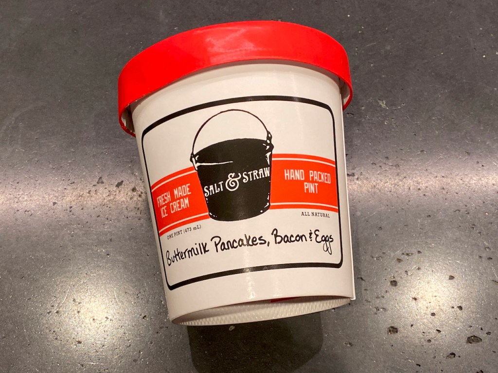 A photo of an ice cream pint and a bowl filled with a weird flavor called buttermilk pancakes, bacon and eggs from Salt & Straw in California. Photo by FoodWaterShoes